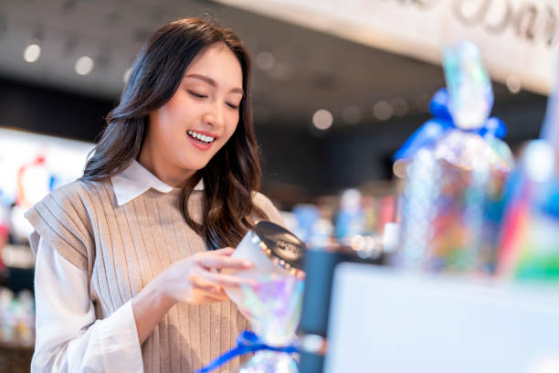 atrakcyjna azjatycka piękna kobieta z torbami na zakupy wybiera kosmetyki i uśmiecha się podczas robienia zakupów w domu towarowym centrum handlowym casual lifestyle - asian ethnicity women shopping mall perfume zdjęcia i obrazy z banku zdjęć