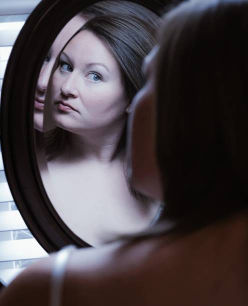 istock Young woman looking at herself in mirror 1478749845