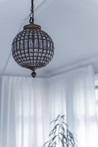 The vertical low-angle view of a circle glass-designed chandelier hung from the ceiling of a room