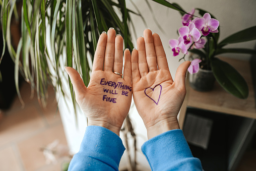 An overhead shot of a young female showing a message of hope written in her hands during coronavirus global pandemic