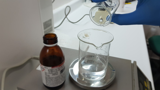 Hand on beaker on white background with test tubes.