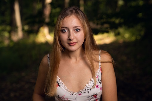 A young female in a beautiful floral dress posing in a forest