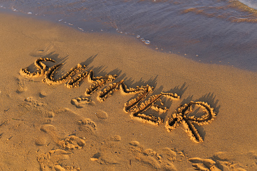 summer written in the sand on a beach near the sea