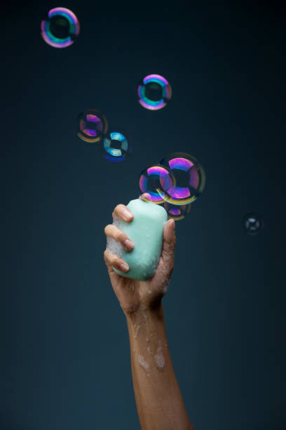 istock Hand holding soap with the bubbles on a dark blue background - beating coronavirus concept 1478756475