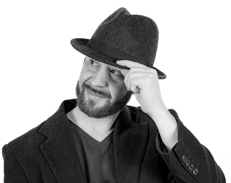 The portrait of handsome man with beard in fedora hat and blazer looking to the left
