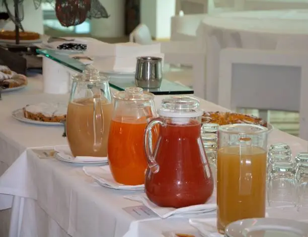 A variety of beverages, including teas and juice, are displayed on a wooden table set with plates and glasses