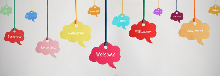 Welcome in different languages ​​on hanging speech bubbles.