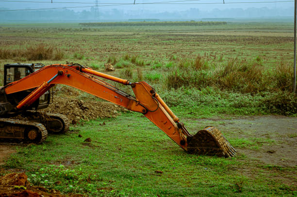 A backhoe loader excavator digger, a heavy industrial vehicle on a green agricultural field.