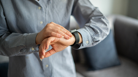 Close-up young businesswoman looking at smart watch at home