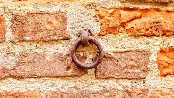 istock Old rusty round chain link sticking out of concrete on a wall 1478765980