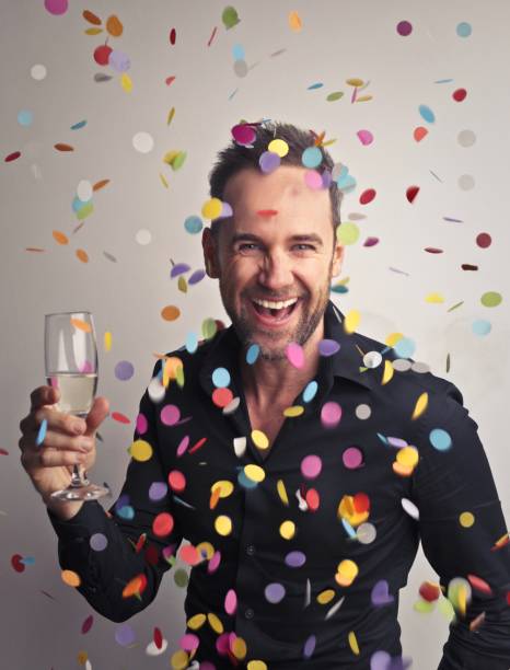istock Cheerful handsome adult man drinking champagne nder the falling confetti 1478767396