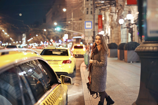 A shallow focus shot of a European female standing near a taxi rank