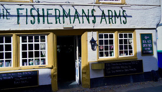 Looe, Cornwall, England, 06 July 2022: restaurants, pubs and shops cater for the many tourists visiting this picturesque estuary and harbour on the Cornish coast. Known for smuggling and fishing.