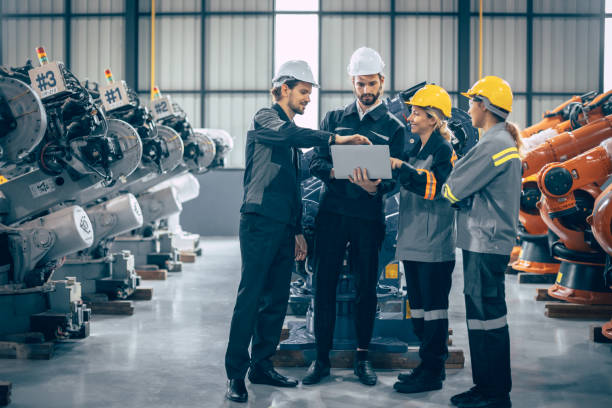 istock Group of engineer team stand talking together. Industry engineering teamwork people discussion. Robot arm design assembly plant meeting with laptop computer for exchange knowledge. 1478772116