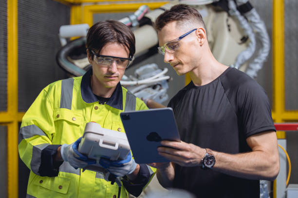 istock engineer team working program robot welding arm in automated factory. robotic specialists talking together in machine industry manufactory 1478772148