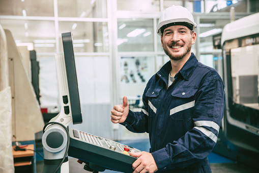 sonrisa feliz pulgares arriba ingeniero trabajador trabajar con máquina de torno CNC en fábrica de metal moderna photo
