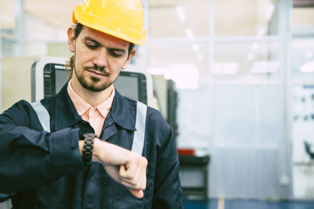 engineer worker looking at wristwatch. industry factory working hours afternoon break times for lunch stock photo