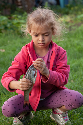 Little cute girl with magnifying glass looking at flower. There is a shallow depth of field.