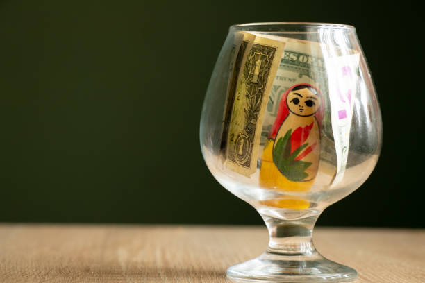 dollars and wooden russian nesting doll in a glass cup on the table