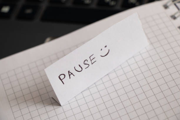 istock Pause and smiley handwritten on a piece of paper and left on a notebook 1478772710