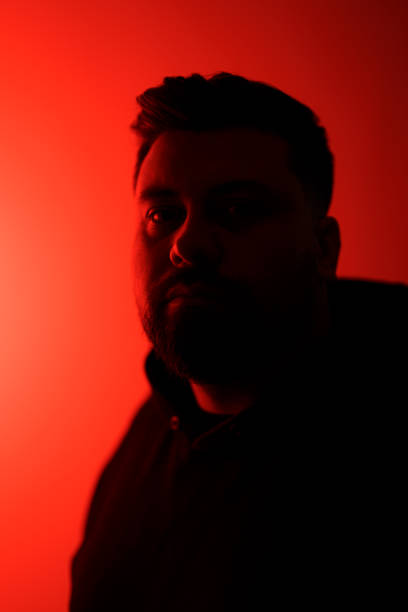istock Serious bearded man in shadow against neon illumination 1478774415