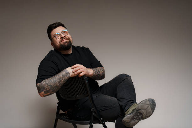 istock Calm bearded and tattooed man sitting on chair in studio 1478774426