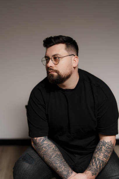 istock Calm bearded and tattooed man sitting on chair in studio 1478774443