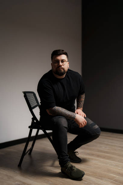 istock Calm bearded and tattooed man sitting on chair in studio 1478774455