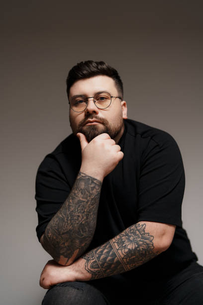 istock Calm bearded and tattooed man sitting on chair in studio 1478774463