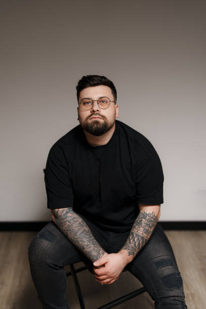 istock Calm bearded and tattooed man sitting on chair in studio 1478774472