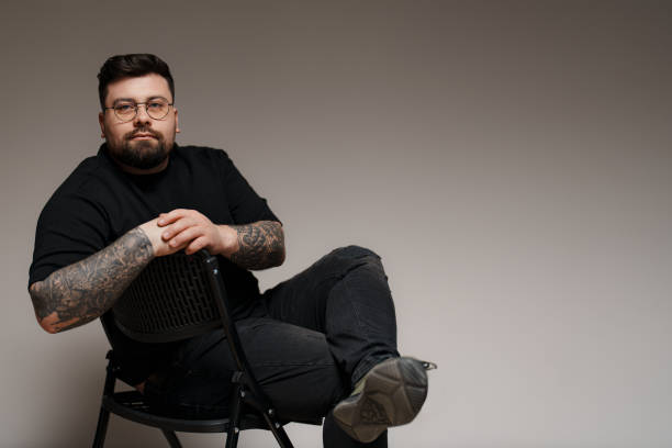 istock Calm bearded and tattooed man sitting on chair in studio 1478774473