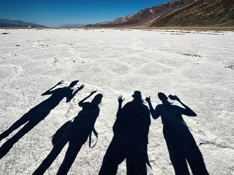A beautiful shot of people's shadows on the ground of the rough landscapes of Death valley