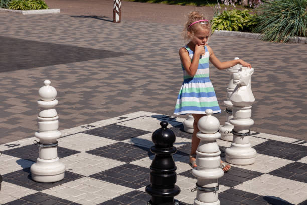 petite fille jouant aux grands échecs de rue - chess skill concentration intelligence photos et images de collection