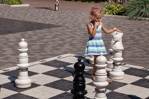 Little girl playing large street chess