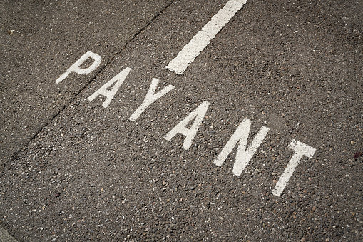 Marking on a street in Colmar in France with the French word Payant. Translation: fee-based parking lot