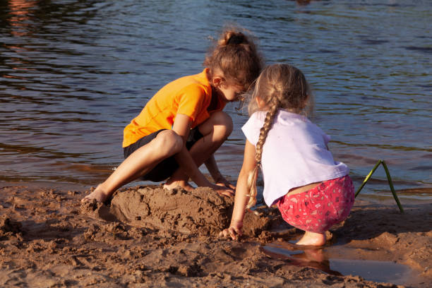 A girl and her younger brother playing at the beach on a late summer morning in Minnesota, USA.
