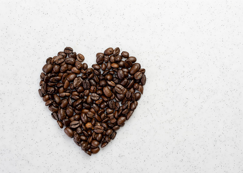 Concept of love or loving coffee. Heart shape made from coffee beans on a white board.