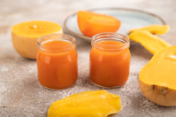 istock Baby puree with pumpkin, persimmon, mango in glass jar on brown concrete, side view, selective focus 1478784023