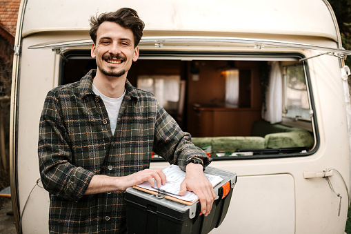Portrait of a male electrician in front of a caravan