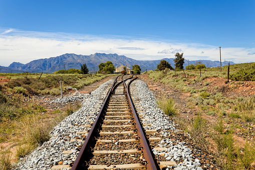A view along railroad tracks towards high mountains in the distance, near Worcester, South Africa.