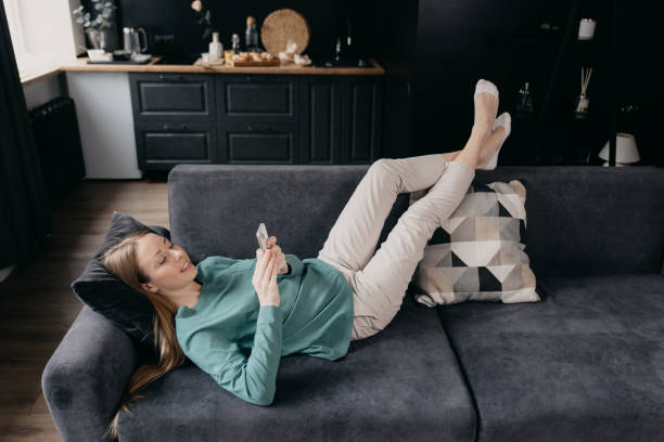 istock woman types text message on cell phone, enjoys online communication lying on couch . Technology, communication concept 1478795128