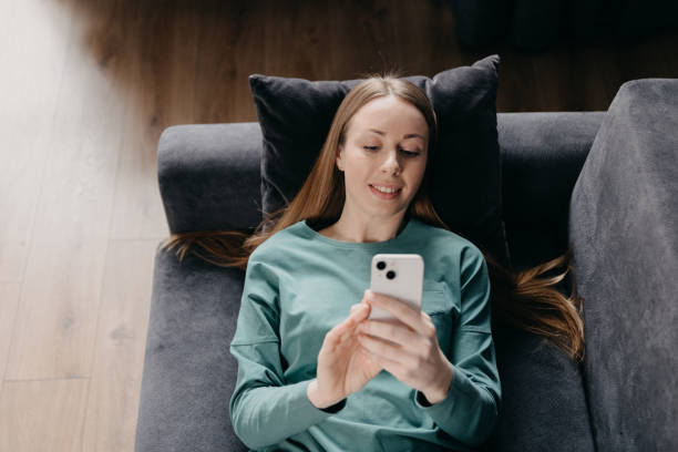 istock woman types text message on cell phone, enjoys online communication lying on couch . Technology, communication concept 1478795304