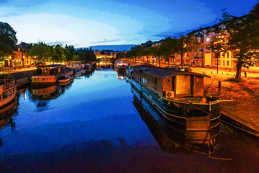 Night view on tributaries of the Loire river and boats along canal and houses of Nantes