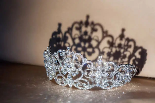 Royal diamond diadem with shadows lying on table. Fairy tale