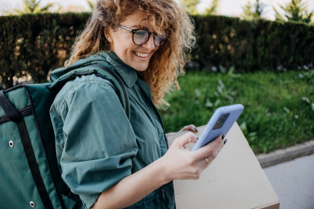 istock Delivery woman is using a mobile phone 1478806641