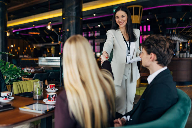 istock Cheerful business woman shaking hands with co-workers in restaurant 1478811348