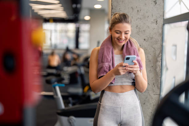istock Fit young woman using mobile phone in gym to watch virtual workout tutorial video 1478822225