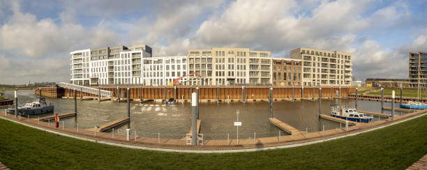 Luxury apartment building rising next to contemporary port Zutphen, Netherlands – January 26, 2021: Panorama of almost finished modern housing project at the north side of the Noorderhaven recreational port panoramic riverbank architecture construction site stock pictures, royalty-free photos & images