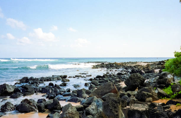 Vintage film photograph of the lava fields of black volcano rock against the blue waters of the ocean on the tropical island of Maui, Hawaii.