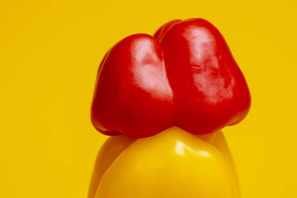 Closeup macro texture and detail of vibrant bright red colorful pepper or paprika stacked on top of a yellow specimen.